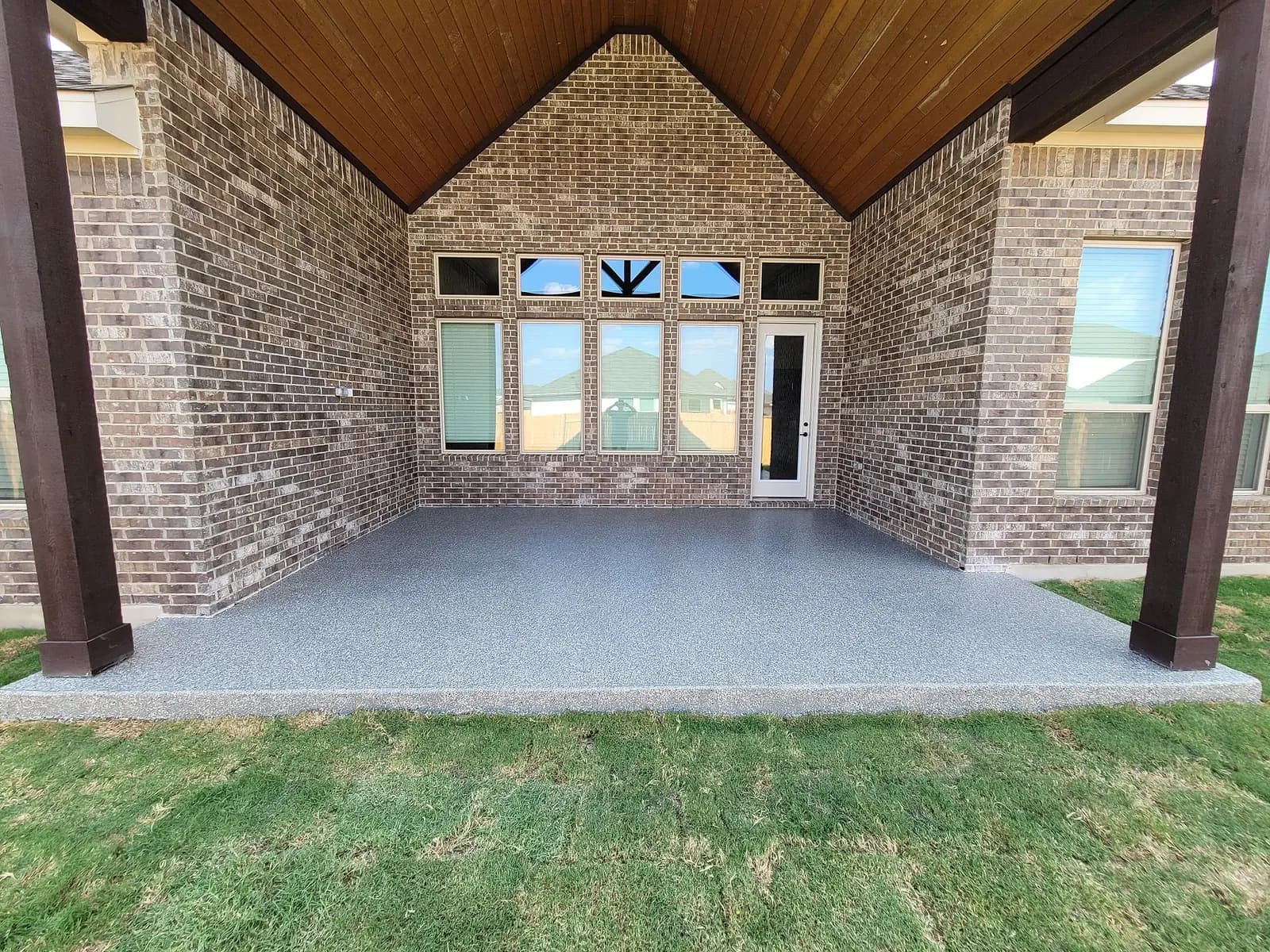 Covered back patio of a brick home with a grey flake floor coating