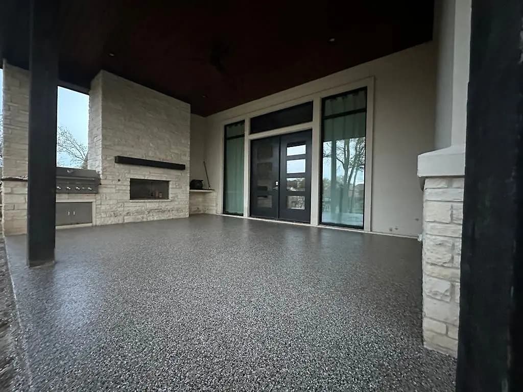 Covered patio with stone columns and a grey flake floor