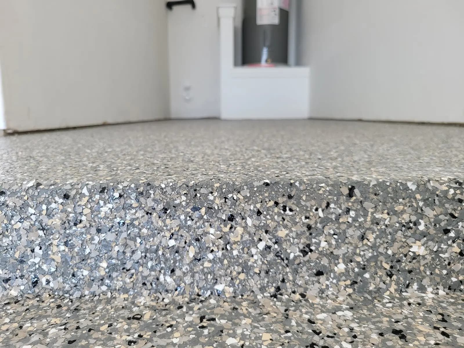 Patio slab coated in a grey flake finish, seen from the edge