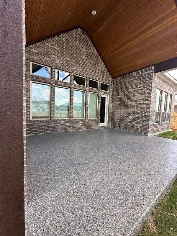 Covered patio of a brick home with a coated floor