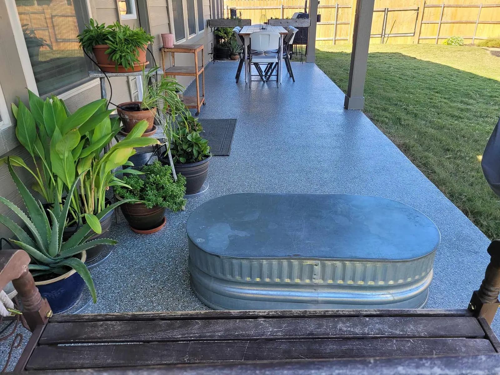 Back porch with potted plants and a stock tank on a coated floor